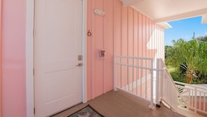 Ein Balkon mit weißer Brüstung, rosa Wänden und einer Tür mit Schloss.