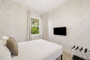 Een hotelkamer met een bed, een aan de muur bevestigde televisie en een raam met gordijnen.