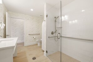Een moderne badkamer met een douchecabine van glas, een witte wastafel en een toilet.