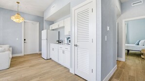 Una cocina moderna con armarios blancos, un refrigerador y una lámpara colgante.