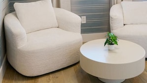 Un salon moderne avec un canapé, une table basse ronde et une grande fenêtre avec des rideaux.