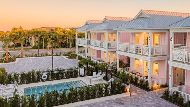 Et hotel med flere balkoner, en swimmingpool og udsigt til palmer.