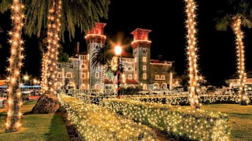 A large building with two towers, surrounded by a garden with star-shaped lights.