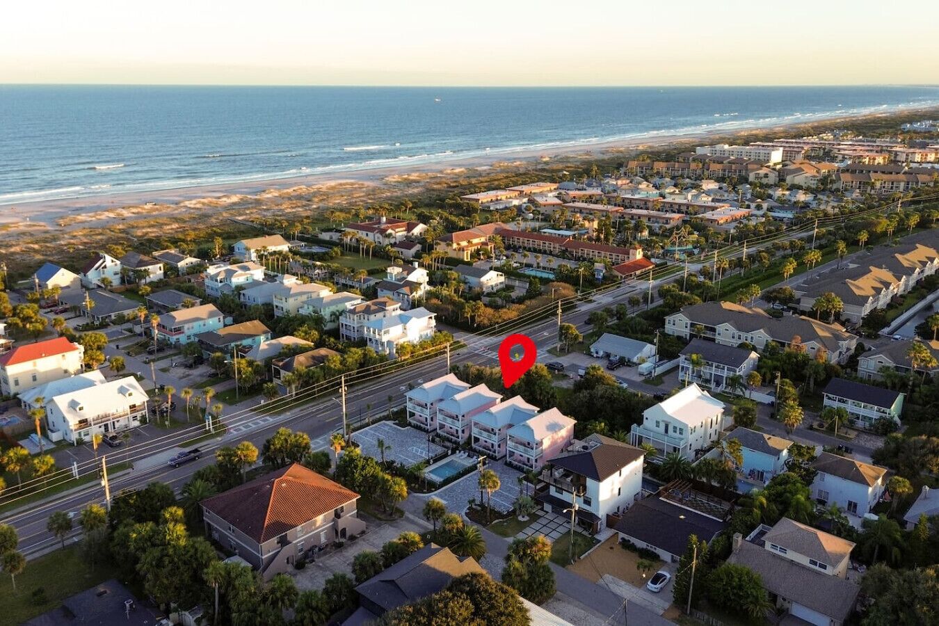 Vue aérienne d’une zone résidentielle côtière, avec des maisons, des routes et une plage.