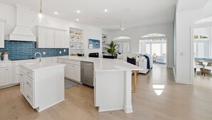 Una cocina amplia con armarios blancos, un salpicadero azul y una isla central.