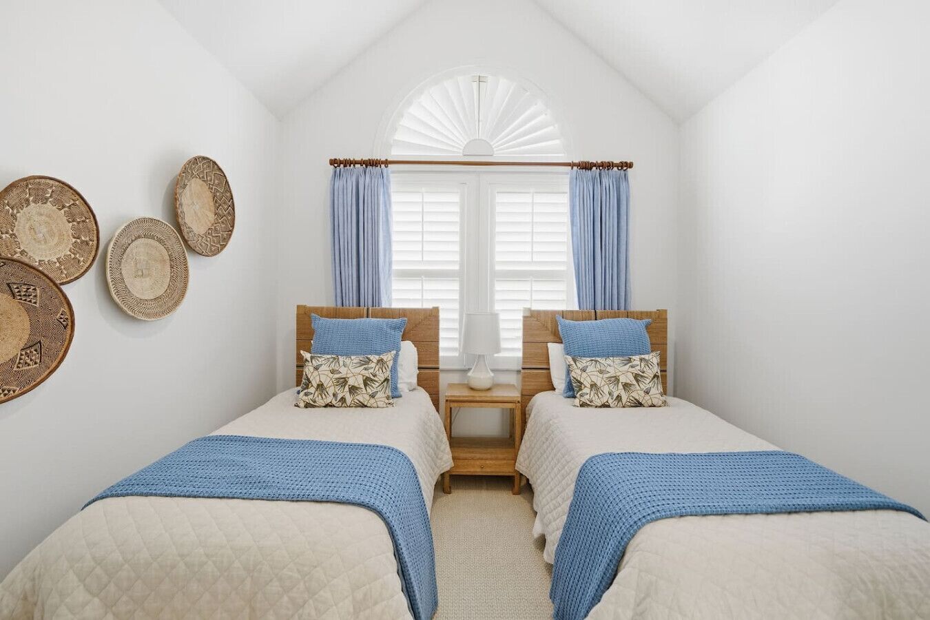 A bedroom with two beds, a window with curtains, and wall decorations.