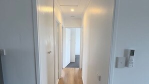 Un pasillo estrecho, bien iluminado, con suelo de madera y paredes blancas.