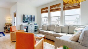 Un soggiorno moderno con un divano grande, una televisione e una zona pranzo con tavolo e sedie.