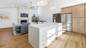 Een moderne keuken met houten kastjes, een roestvrijstalen koelkast en een centraal eiland met lades.