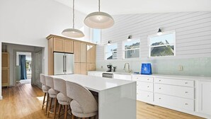 Een moderne keuken met een centraal eiland, houten kasten en hanglampen.