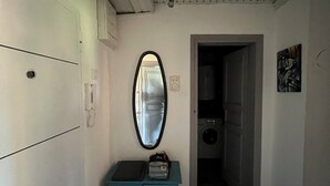 Um corredor estreito com um armário azul, um espelho e um ventilador de teto.