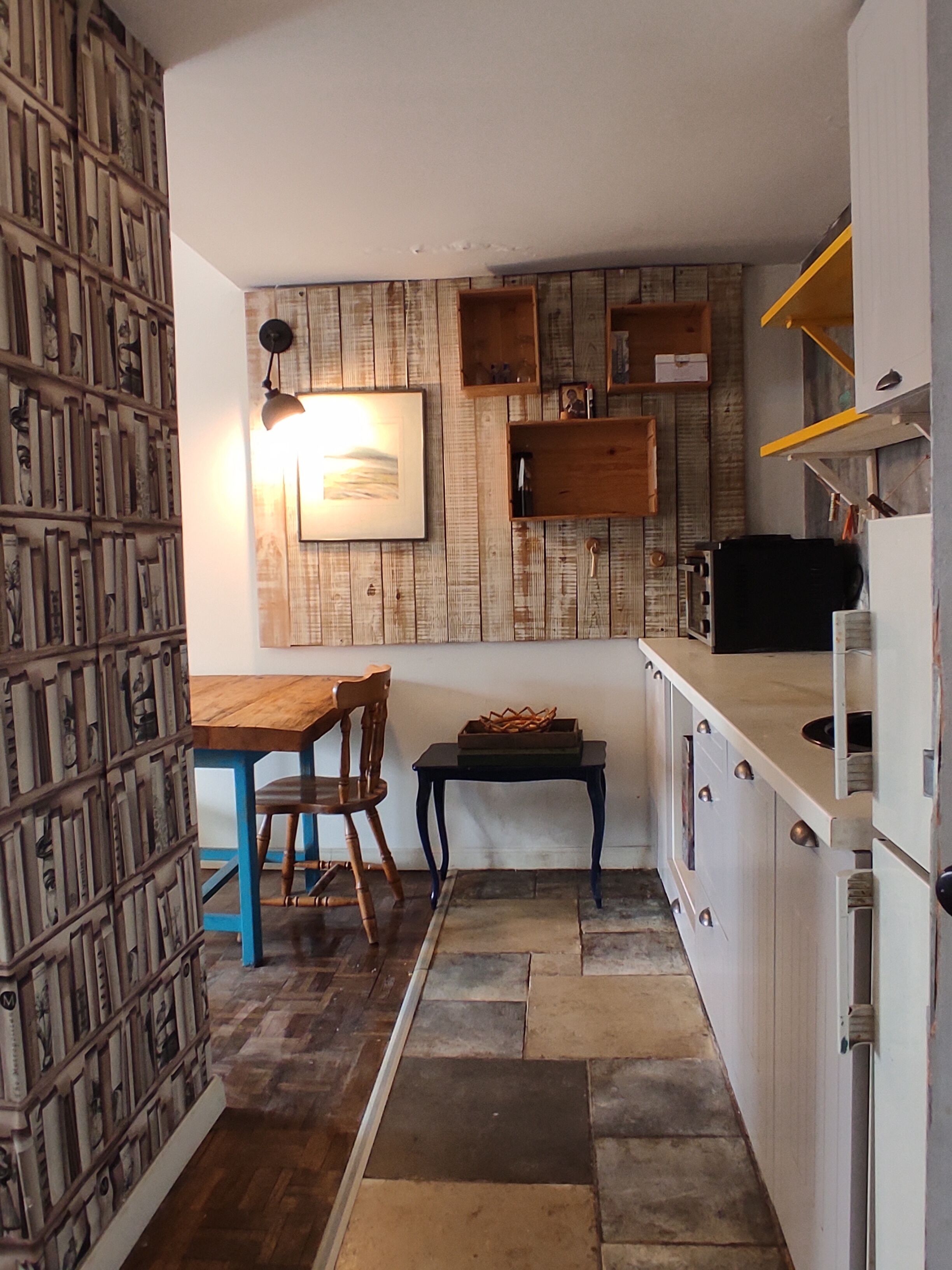 Une cuisine compacte avec un mur en bois, une table à manger avec des chaises et un petit îlot central.