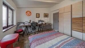 Quarto com cama, escrivaninha, cadeira, radiador e janela.