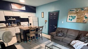 Um espaço compacto com cozinha compacta, área de refeições e sala de estar com sofá e mesa de centro.