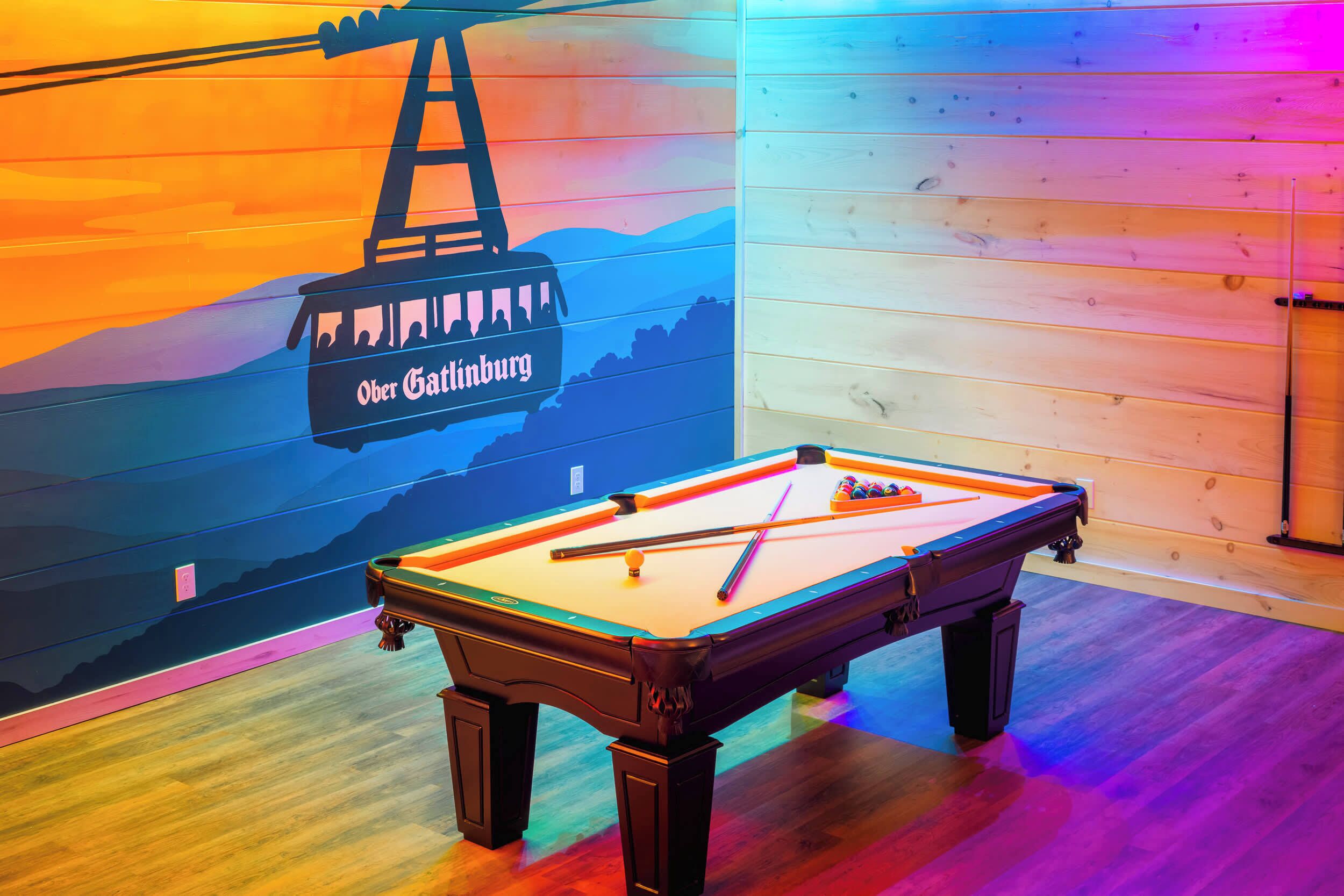 Una mesa de billar en una sala con paredes de madera y un mural de un teleférico.