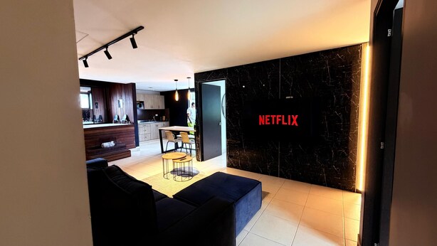 A modern living room with a black wall, a blue sofa, and a dining area with a table and chairs. - LUXURY POBLADO PARK (Medellín)