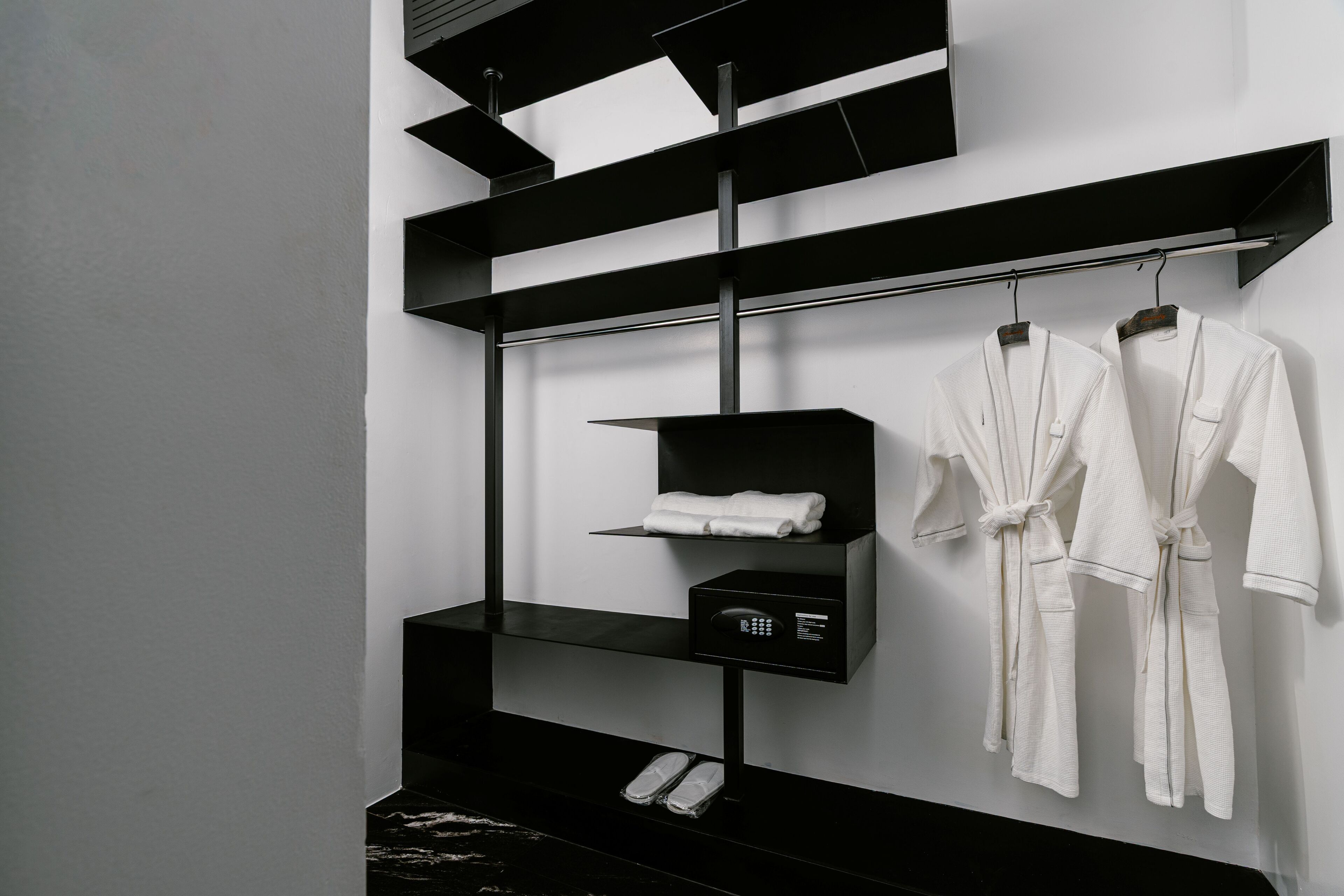 A modern bathroom with black shelves, a towel rack, and a telephone.