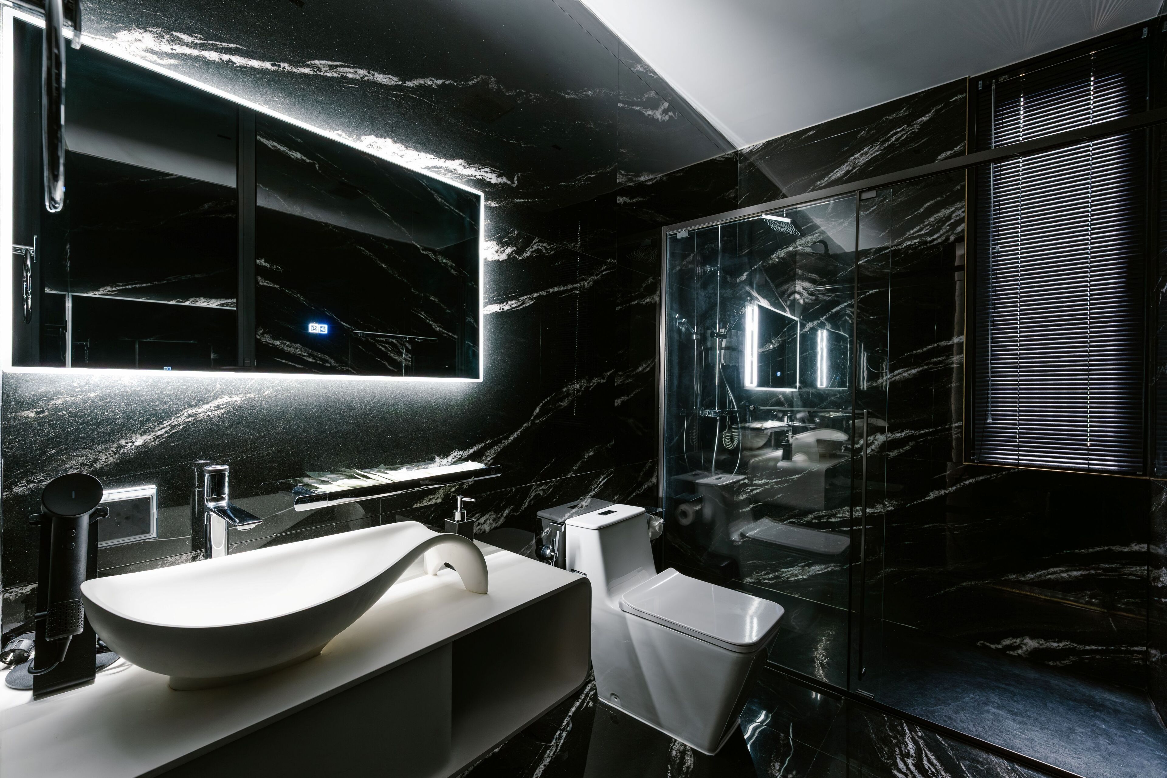 A modern bathroom with a large mirror, a white sink, and a glass-enclosed shower.