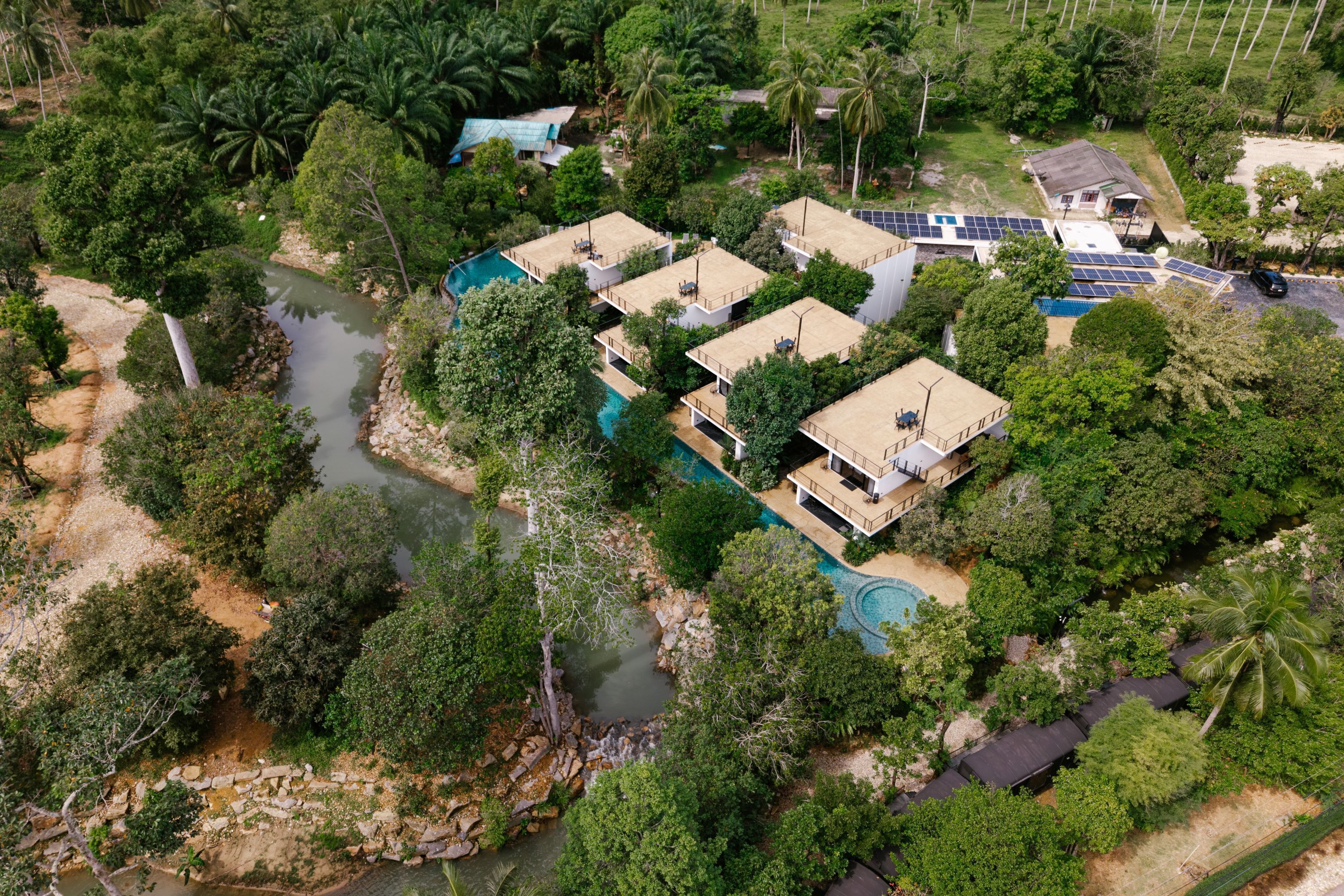A resort with multiple buildings, a swimming pool, and a river.