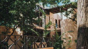 Un patio con una cerca de metal, plantas en macetas y un edificio con balcones.
