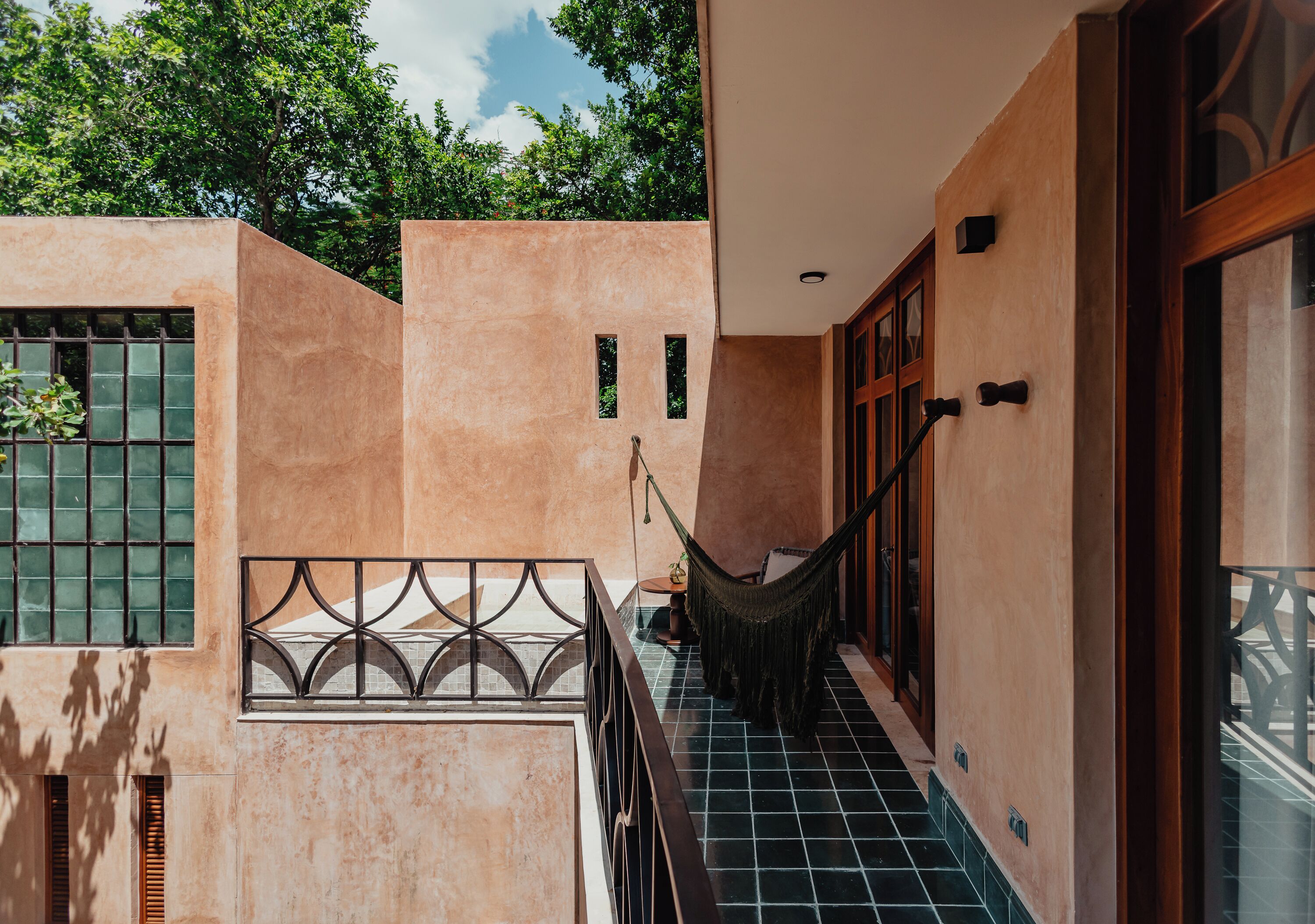 A corridor with a hammock, a window with bars, and a door with a wooden frame.