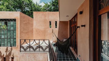 A corridor with a hammock, a window with bars, and a door with a wooden frame.