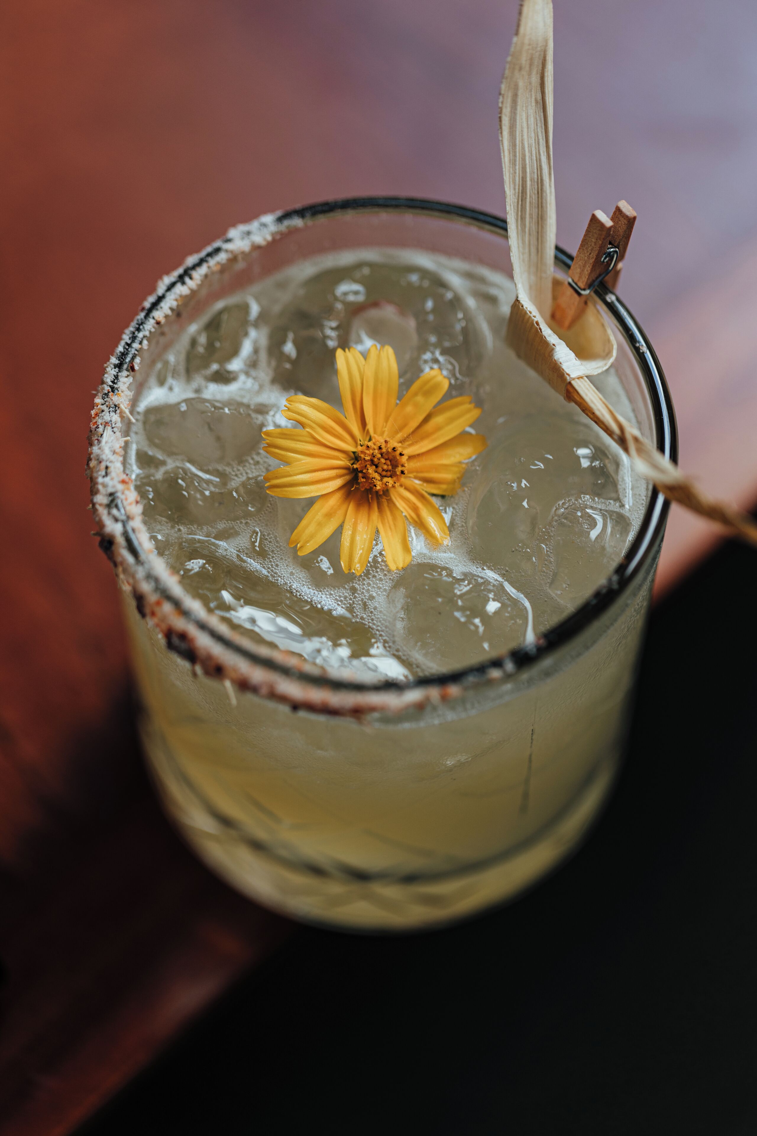 A glass with a flower garnish, ice cubes, and a straw.