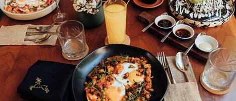 A breakfast setting with a plate of eggs, toast, and a glass of orange juice.