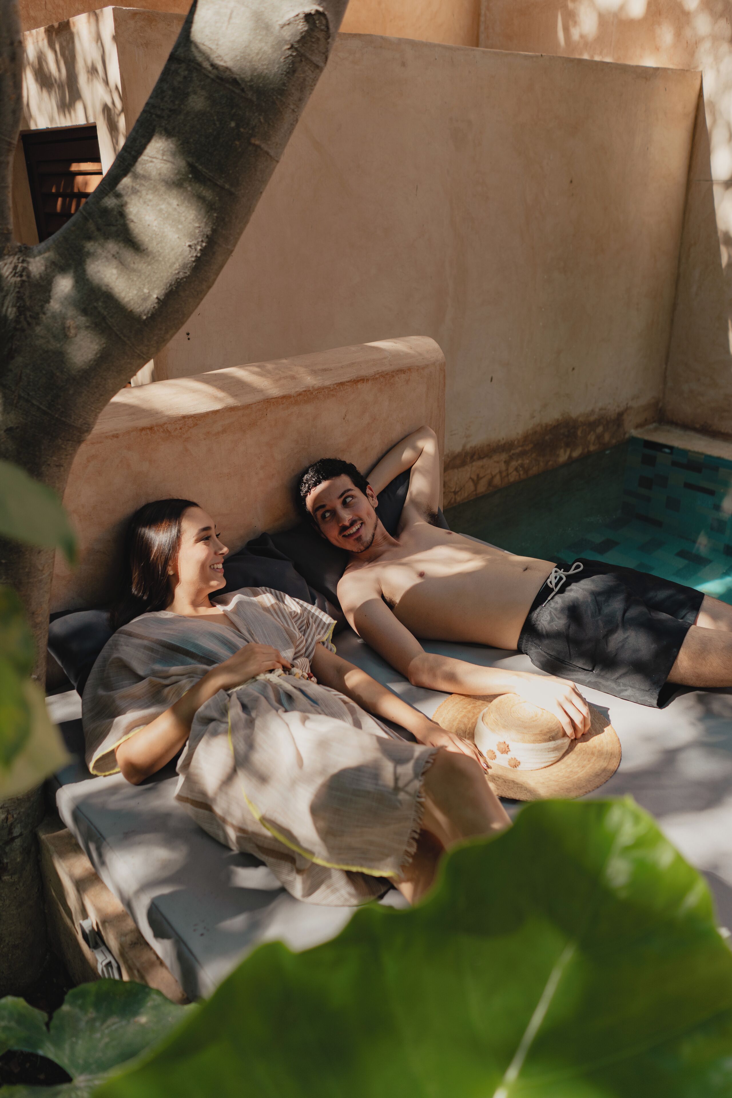 A couple lying on a bed with a view of a swimming pool.
