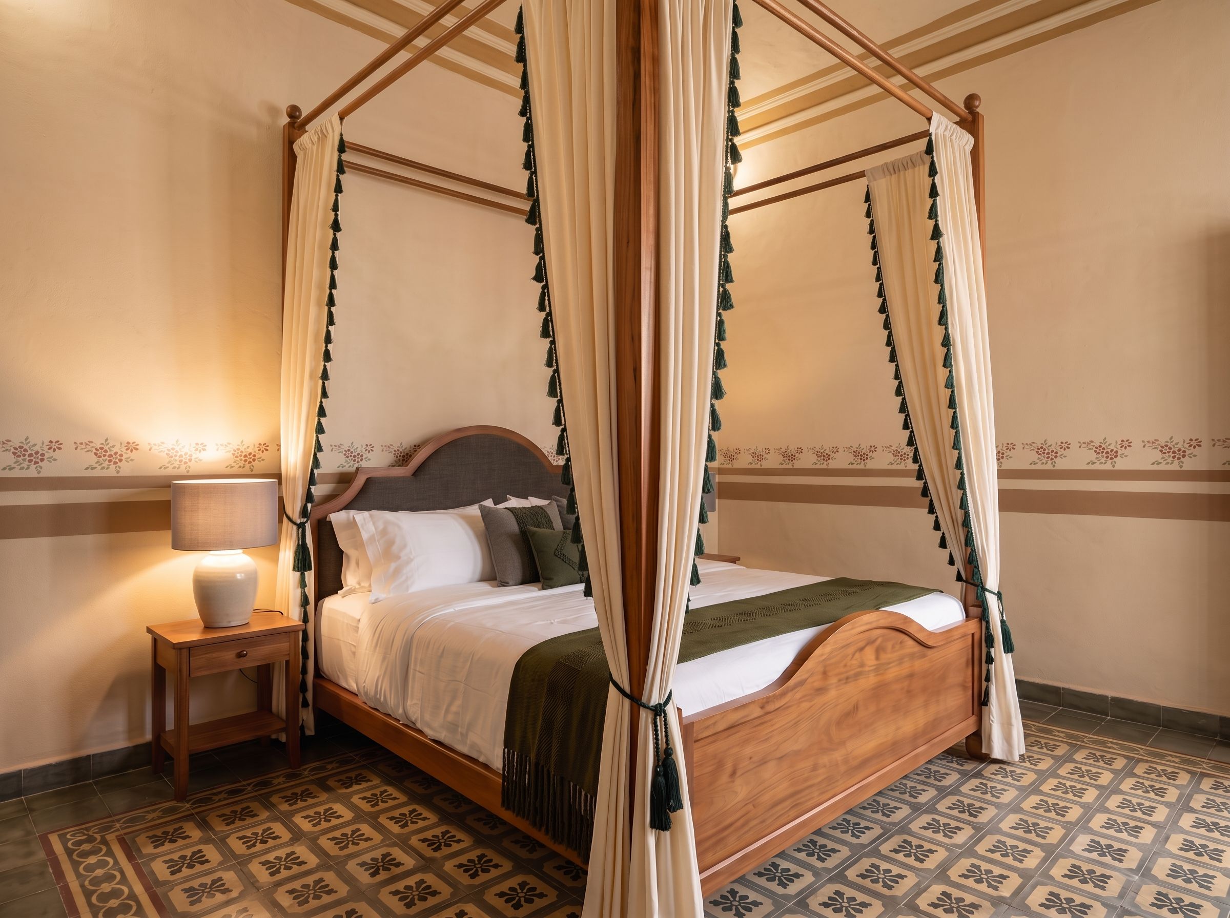A four-poster canopy bed with a wooden headboard, a bedside table with a lamp, and patterned floor tiles.