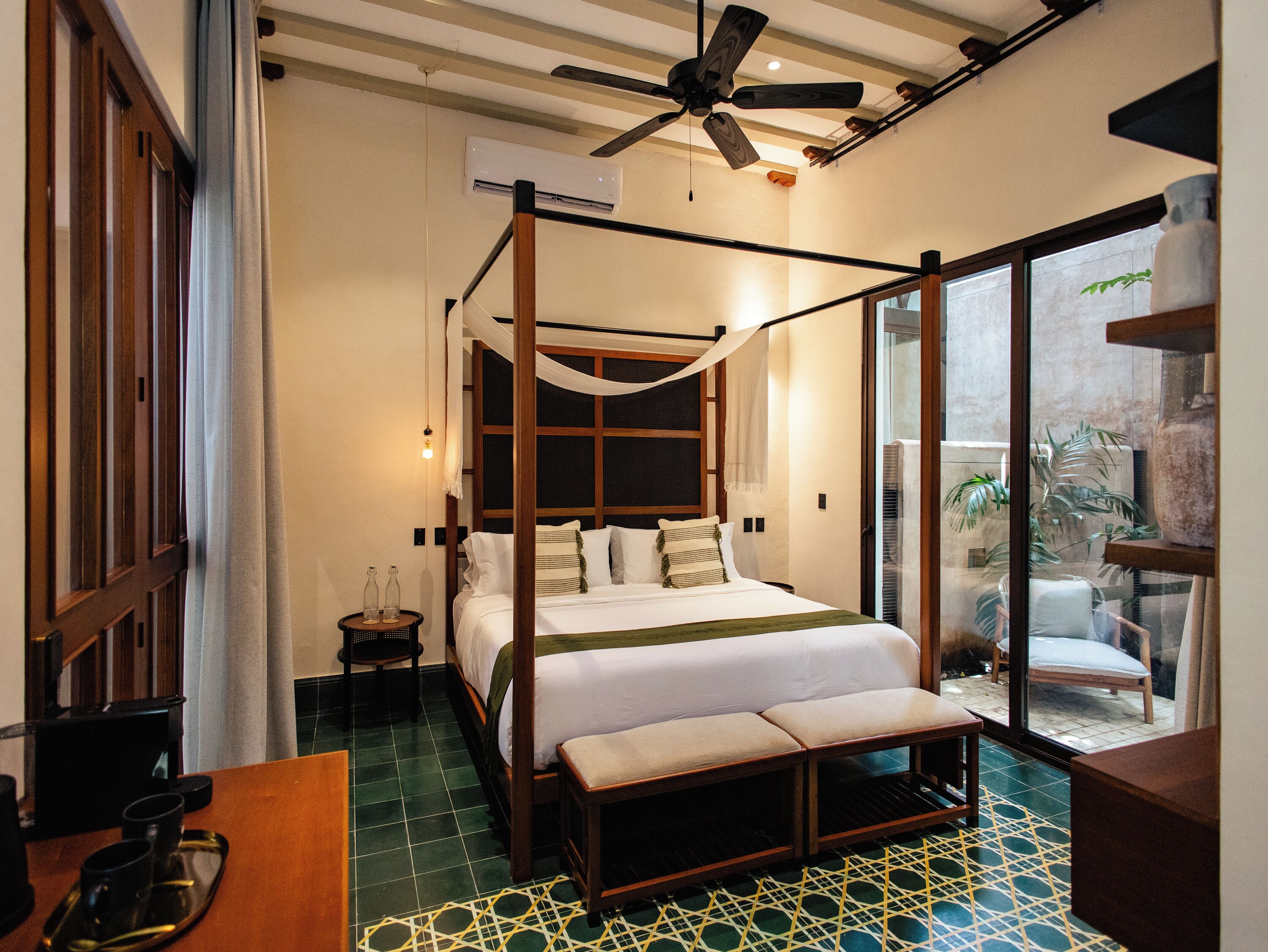 Quarto com cama de dossel, ventilador de teto e vista através de uma porta de vidro.