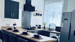 Una cocina moderna con armarios oscuros, una isla de mármol y lavadora integrada.