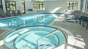 An indoor swimming pool with clear water, sunlit by large windows, and surrounded by lounge chairs. - Harbor Springs Adventure Base—Beach, Trails & Skiing (Harbor Springs)