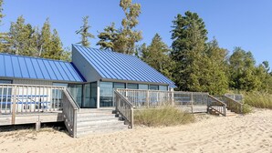 A beachside building with a blue roof, wooden deck, and glass doors. - Harbor Springs Adventure Base—Beach, Trails & Skiing (Harbor Springs)