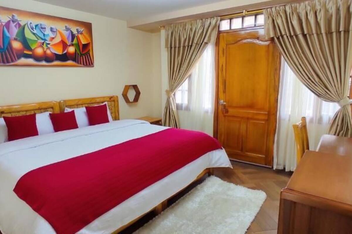 Ein Schlafzimmer mit einem großen Bett, einem Holzkopfende, einem Gemälde an der Wand und einer Holztür.
