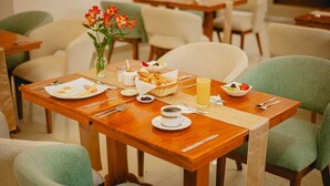 A dining table set with plates, cutlery, a basket of bread, a bowl of fruit, and a glass of juice. - HOTEL LA JOYA (Otavalo)
