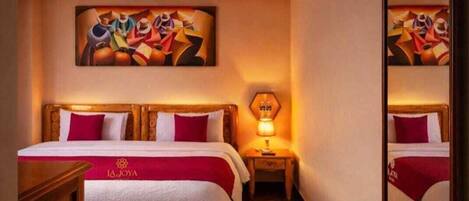 Una camera d'albergo con un letto, una scrivania, un comodino con una lampada e un quadro appeso al muro.