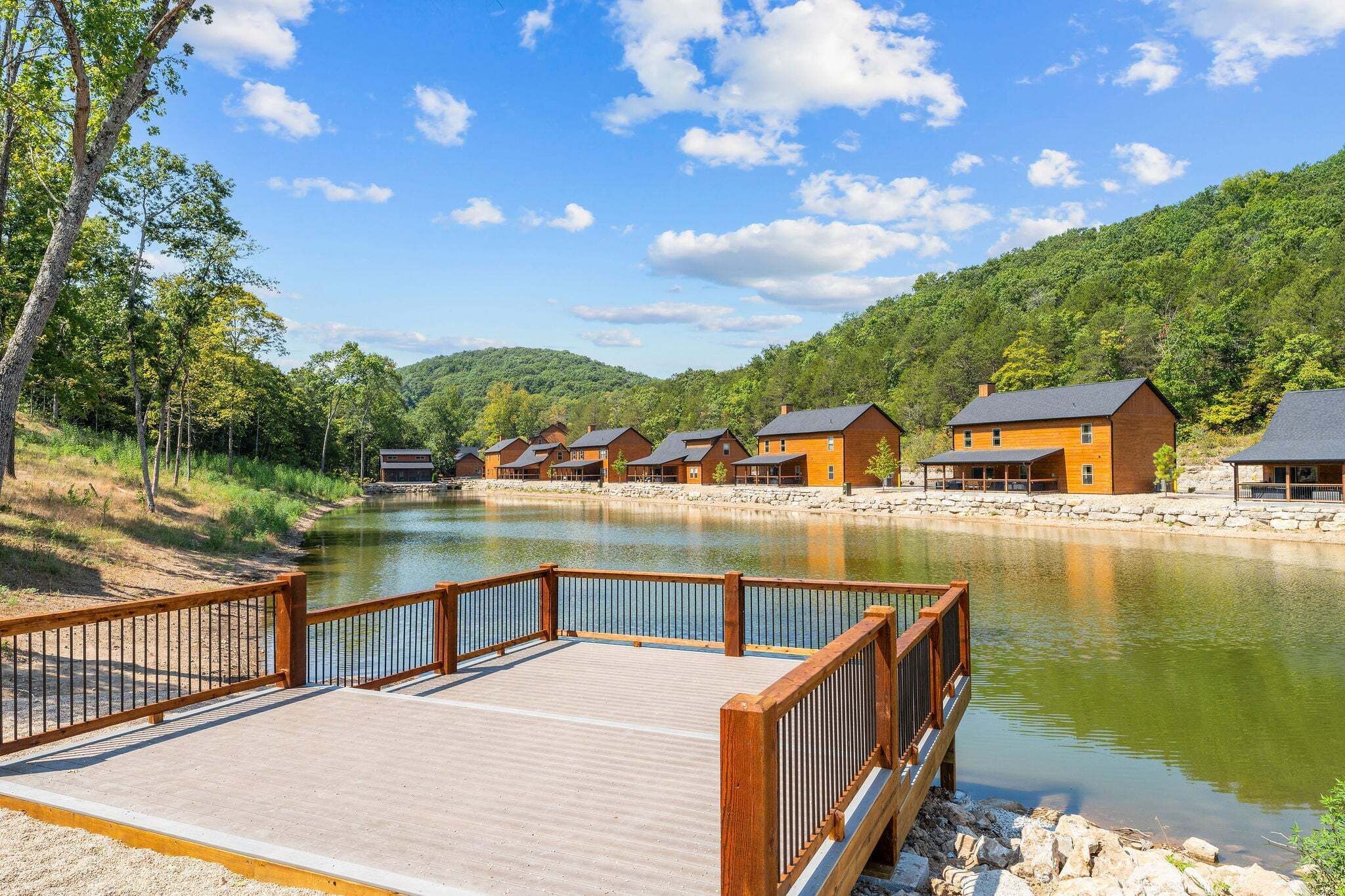 A lakeside hotel with wooden cabins, a wooden deck, and a stone pathway.