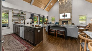 Una cocina amplia con una isla grande, techo de madera y chimenea de piedra.
