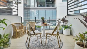 A balcony with wicker chairs, a round table, and potted plants. - 5min stroll to QPAC & Southbank with free parking (South Brisbane)