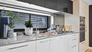 A modern kitchen with a large window, stainless steel appliances, and white cabinetry. - 5min stroll to QPAC & Southbank with free parking (South Brisbane)