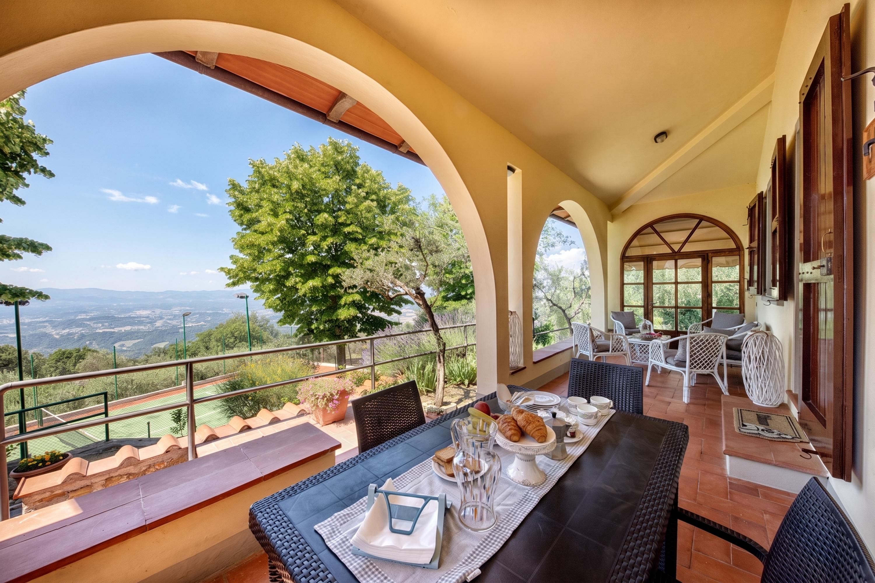 Una terraza con mesa lista para comer, con vistas a un paisaje pintoresco.