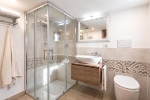 A modern bathroom with a glass shower enclosure, a wooden vanity, a white sink, and a toilet. - Tuscany Apt Marco Private Pool&Tennis 6, Loro Ciuffenna, Italy (Loro Ciuffenna)
