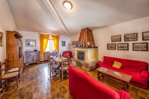 A spacious living area with a red sofa, a dining table, and a fireplace. - Tuscany Apt Marta Private Pool&Tennis 6, Loro Ciuffenna, Italy (Loro Ciuffenna)