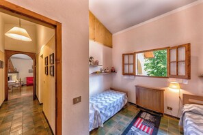 Ein Schlafzimmer mit einem Bett, einem Fenster mit Blick, einem Heizkörper und einer Tür zu einem anderen Raum.