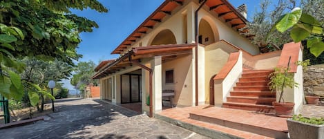 Un edificio con tejado de baldosas, ventanas de arco y entrada empedrada.