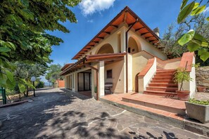 Un edifici amb teulada de rajola, finestres d'arc i entrada d'un paviment de pedra.