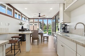 A modern kitchen with a dining area, large windows, and a ceiling fan. - Serene 3-bedroom house in Redondo Beach perfect for relaxing stays (Redondo Beach)