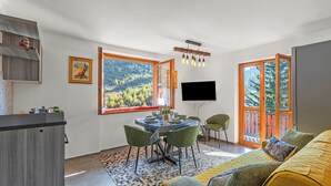 Un saló modern amb zona de menjador, grans finestres i televisió plana.