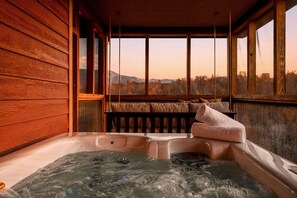 Banheira de hidromassagem em cabana de madeira com vista para montanhas.